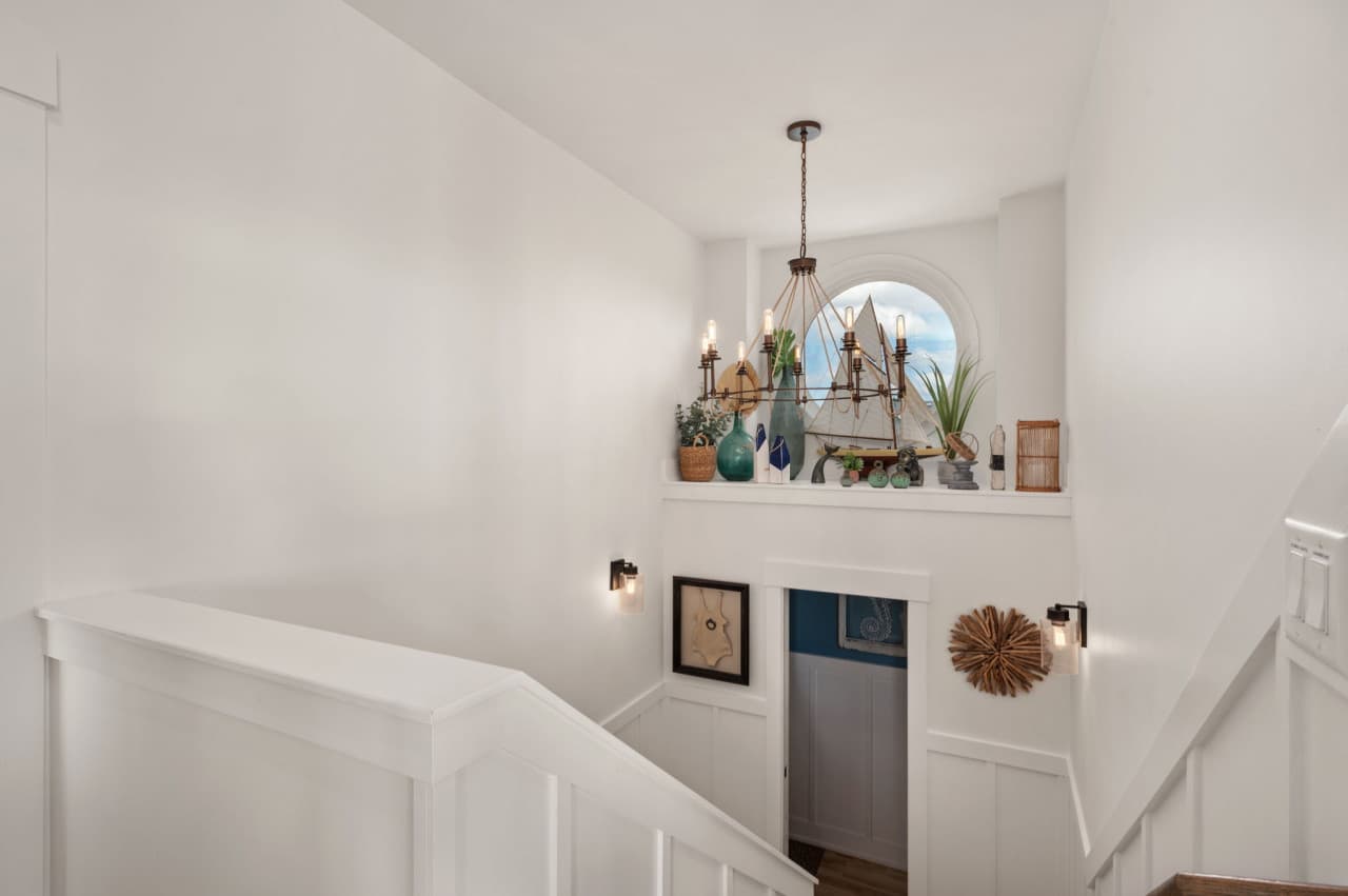 Bright stairwell w/ coastal art & crisp white walls that keep the space light and airy.