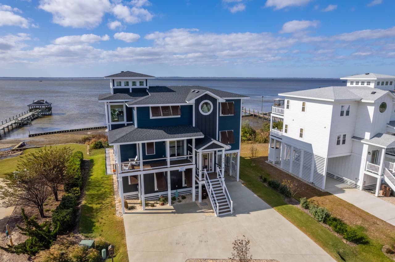 Elevated exterior view highlighting the home’s striking design set against calm coastal waters.