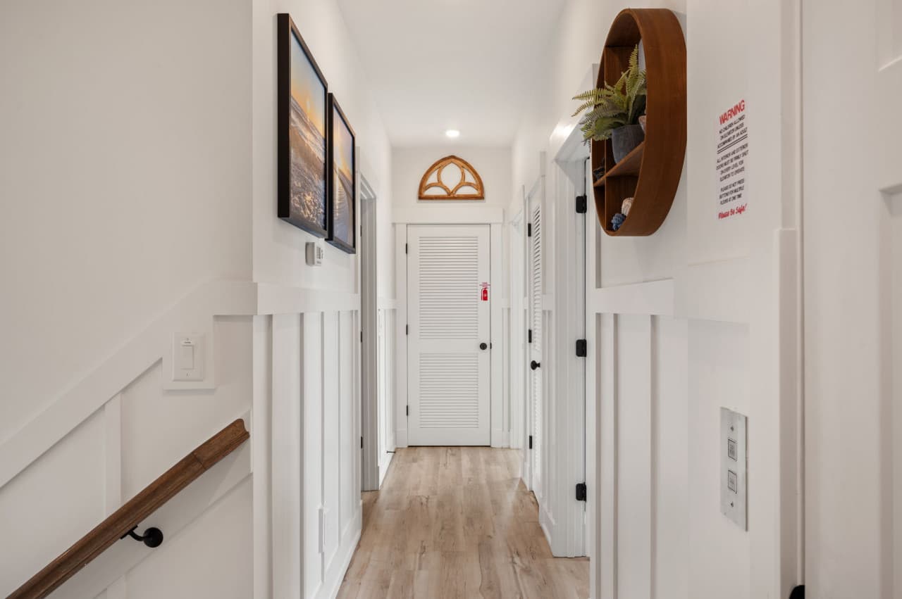 Clean hallway w/ coastal décor, white doors & a fresh, uncluttered feel.