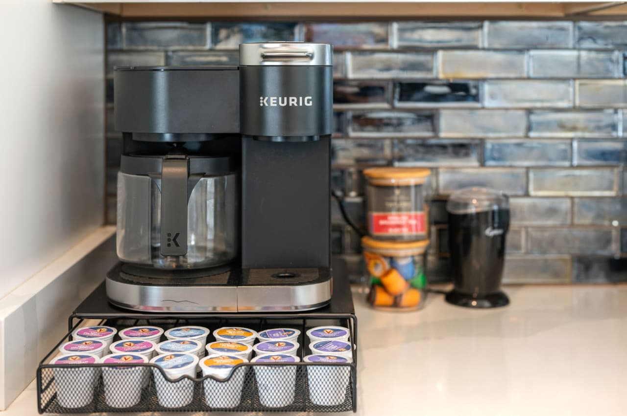 Coffee station w/ modern appliances & tiled backsplash for easy morning routines.