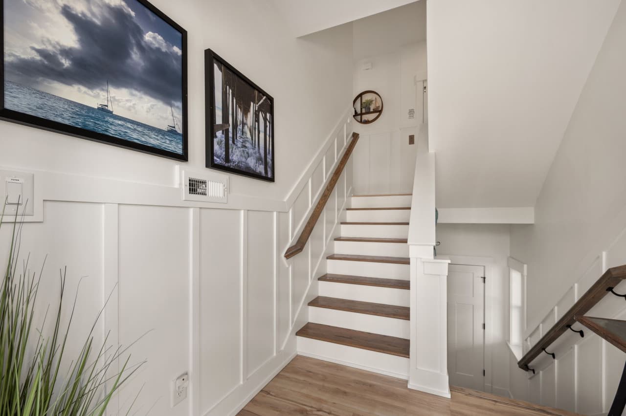Bright staircase w/ wood treads, coastal art & an open, welcoming feel.