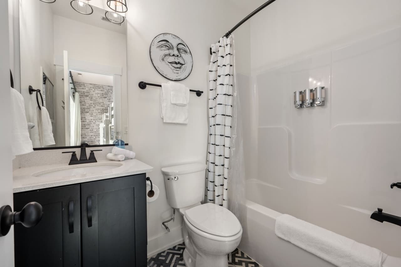 Charming bathroom w/ patterned curtain, playful details & bright white finishes.