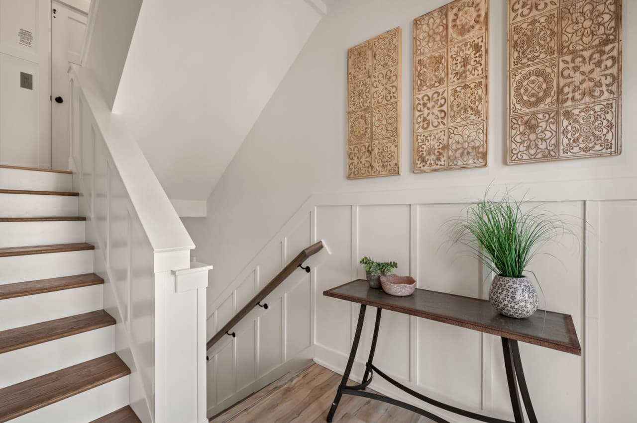 Welcoming stair landing w/ coastal art, light wood accents & a bright, open feel.