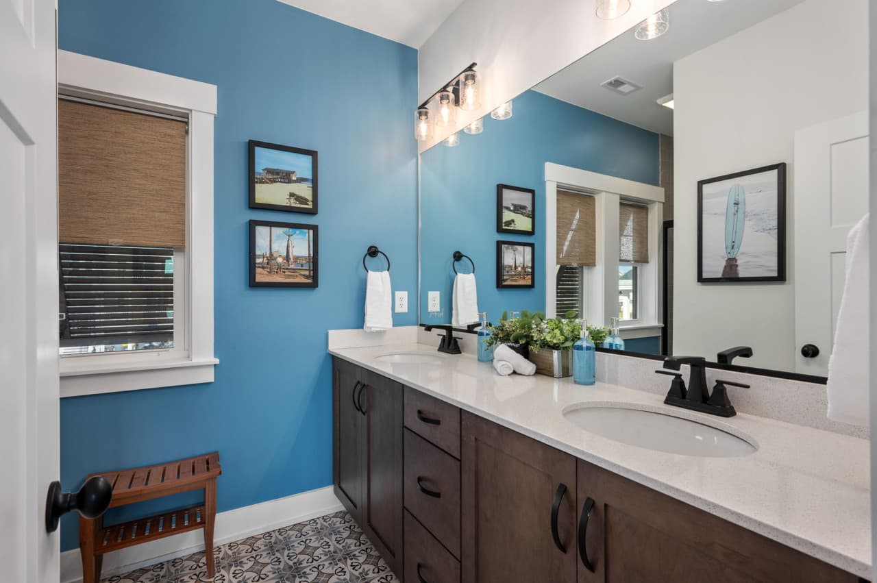Spacious double vanity w/ blue walls, warm wood tones & modern fixtures.