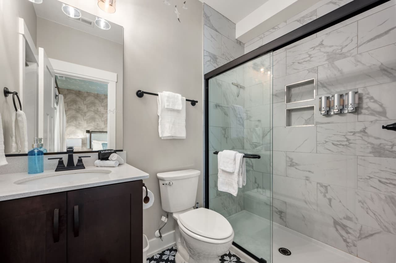 Glass walk-in shower w/ marble-style tile & sleek fixtures for a spa-like feel.