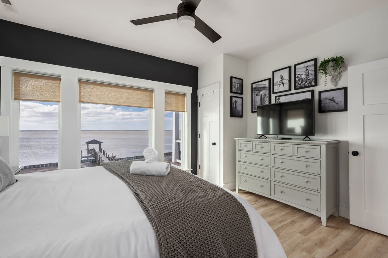 Cozy bedroom w/ soft bedding, framed art & natural light that sets a relaxed tone.