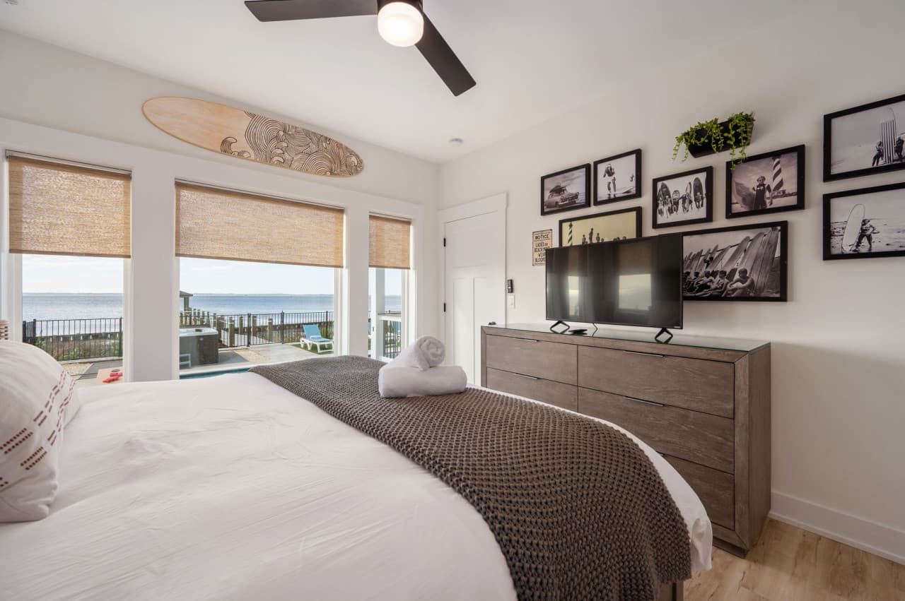 Inviting bedroom w/ plush bedding, framed photos & easy access to the outdoors.