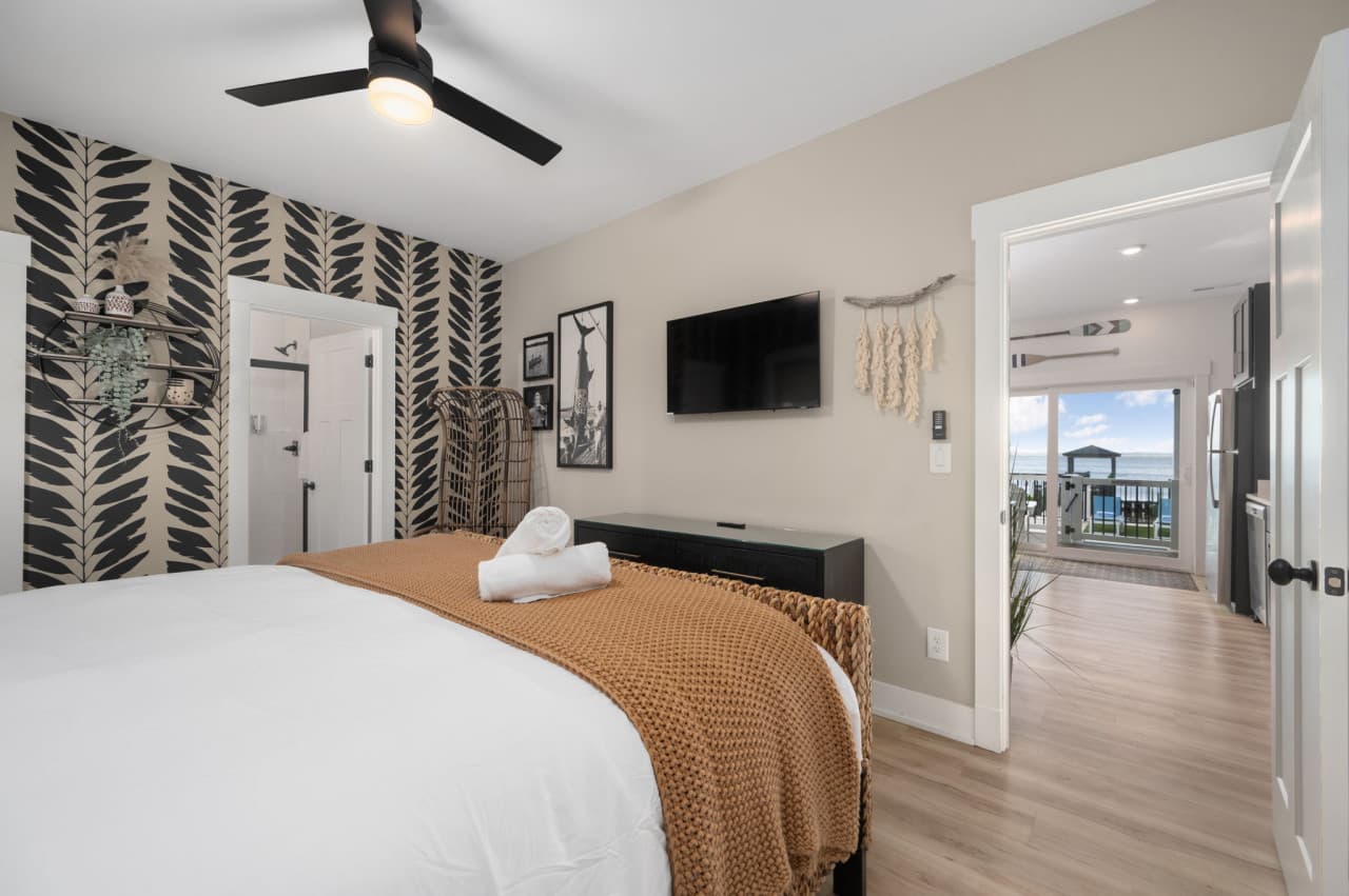 Comfortable bedroom w/ warm textures, wall-mounted TV & an easygoing layout.
