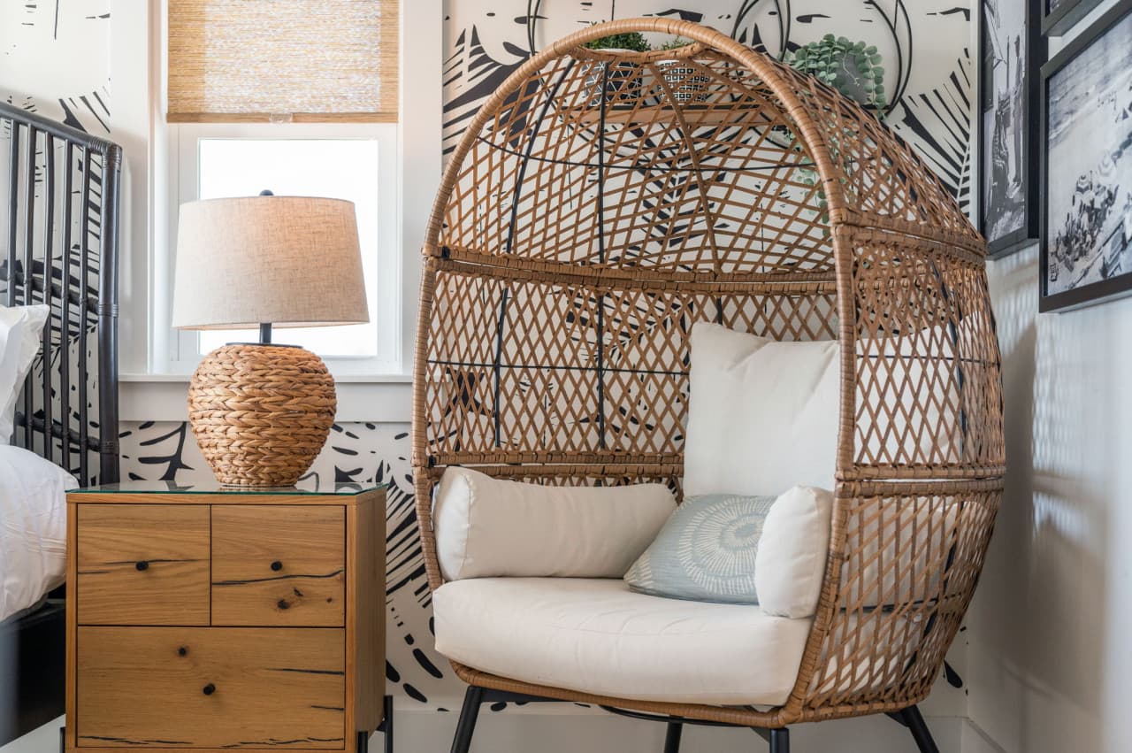 Corner of the bedroom w/ a hanging rattan egg chair — a comfy spot to sit and read.