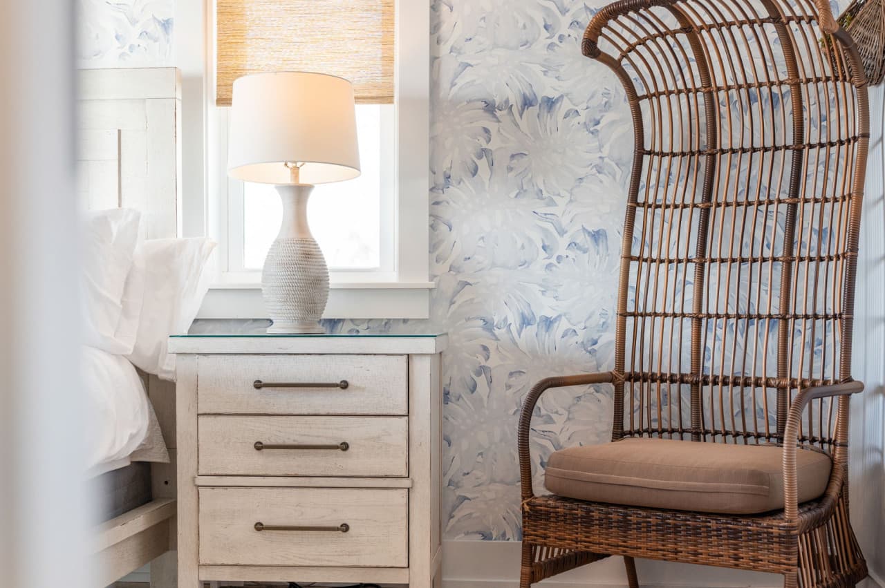 Detail of the nightstand & rattan chair beside the bed, all soft neutrals and texture.
