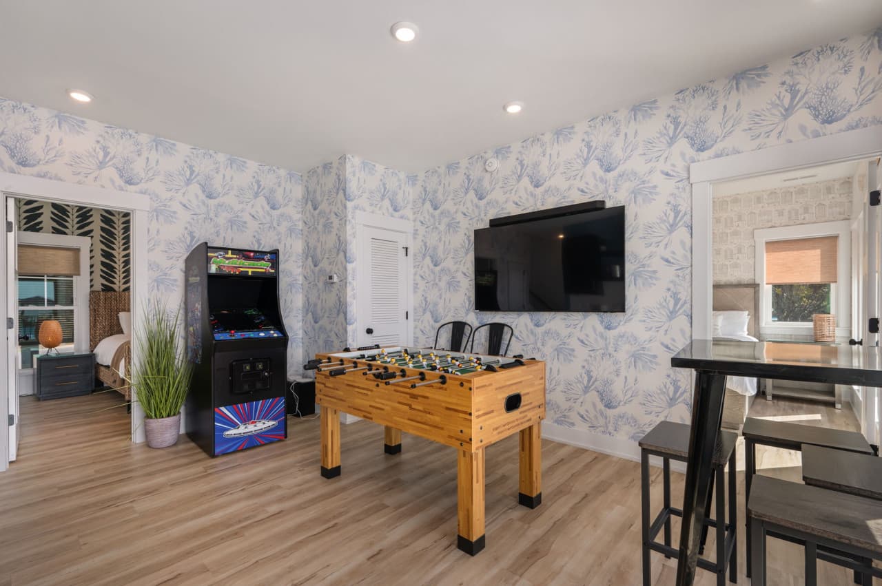 Game room w/ arcade cabinet, foosball & a wall TV plus high-top seating for the group.