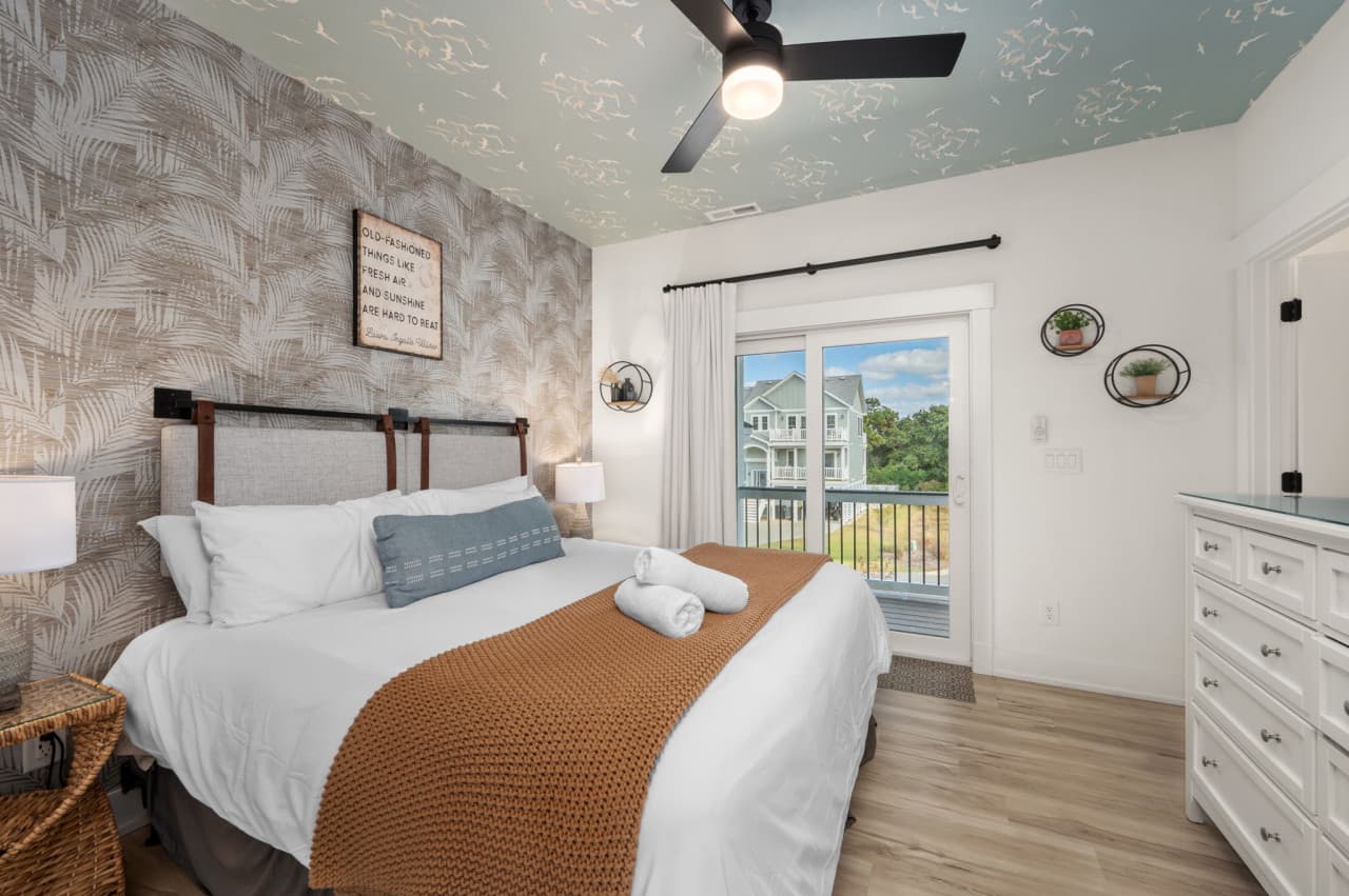 Bedroom w/ a textured accent wall, dresser & a slider out to a private balcony.