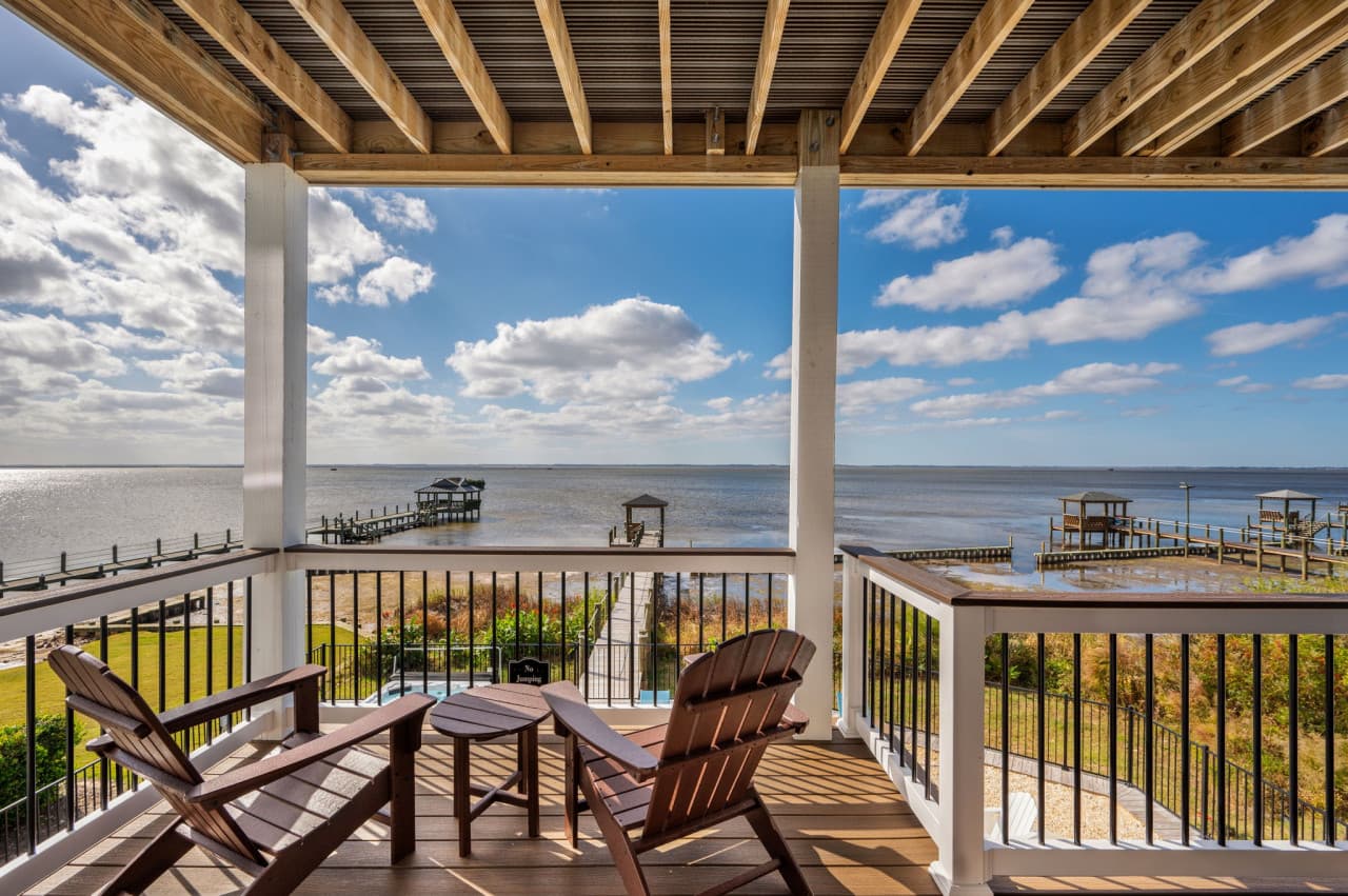 Covered deck w/ Adirondack chairs looking straight out over the sound and the pier.