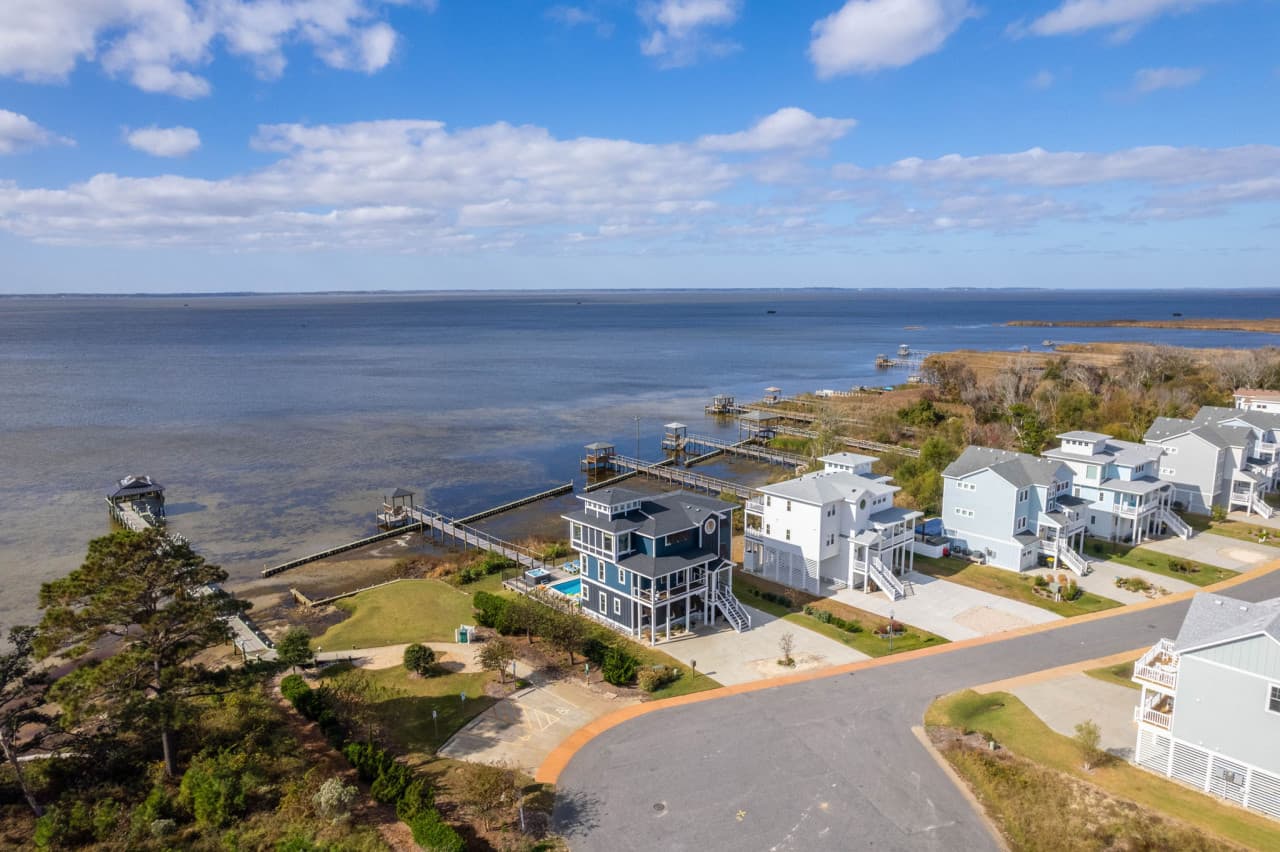 Aerial of the soundfront neighborhood w/ private piers reaching out into the water.