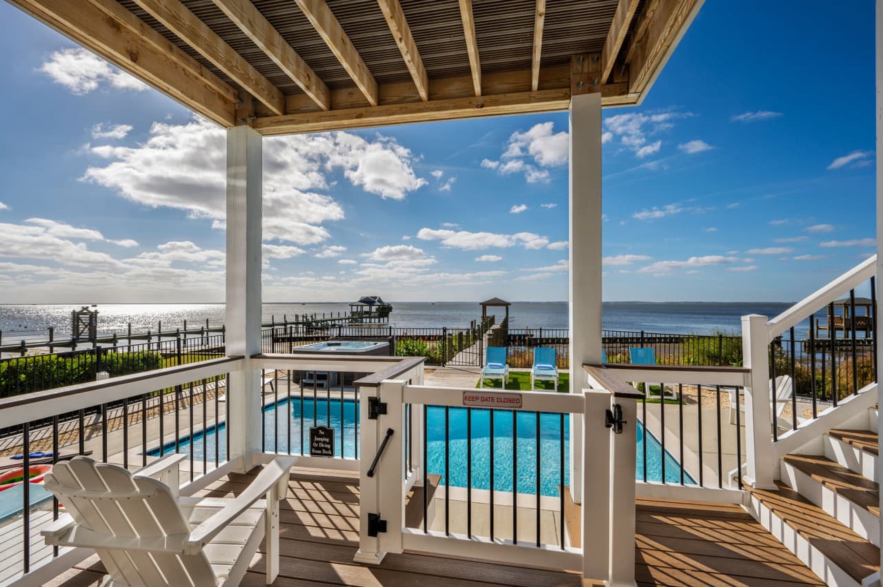 Covered porch looking down over the private pool w/ the sound stretching out behind.