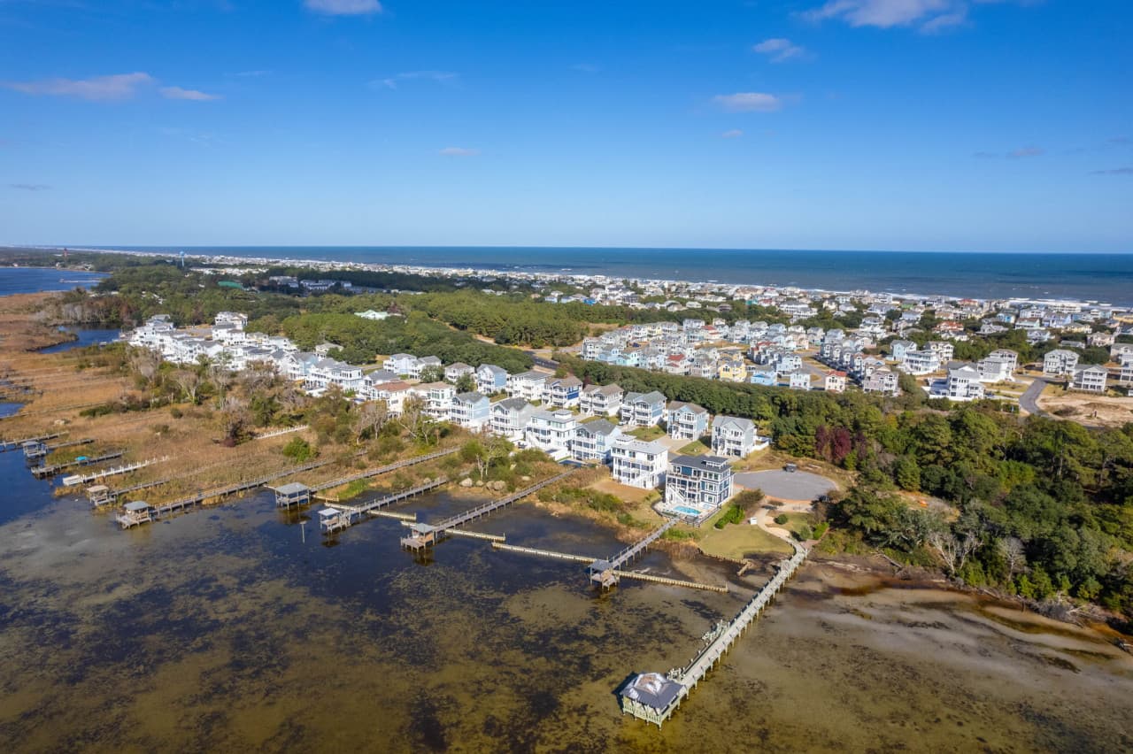 Aerial of the neighborhood w/ piers, marsh & the sound wrapping the shoreline.