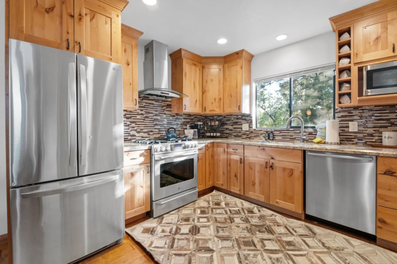Discover culinary delight: A charming kitchen with wood accents & modern appliances ( stove, refrigerator, dishwasher, microwave)