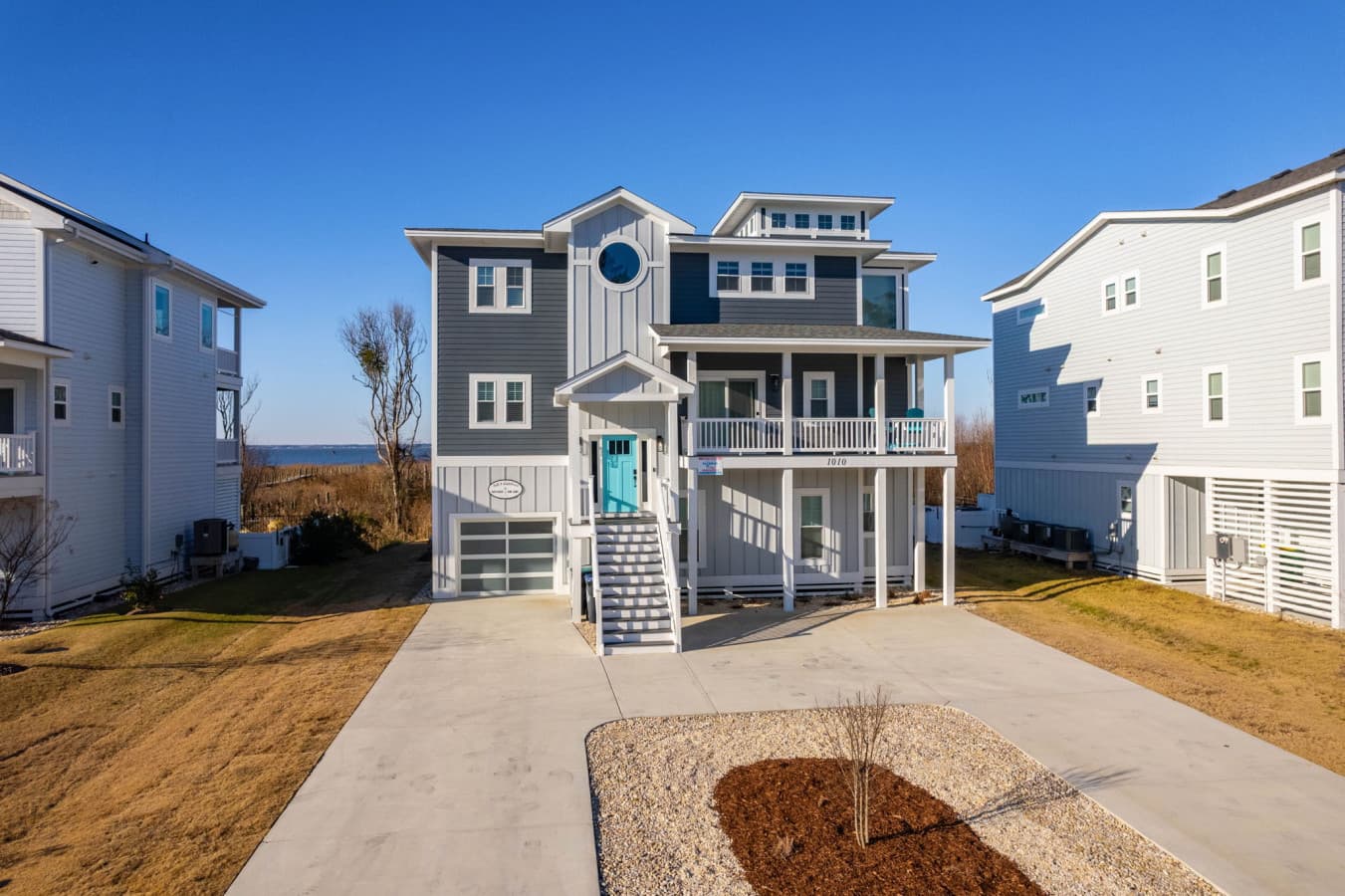 Classic coastal exterior w/ balconies & clean lines, nestled among neighboring coastal homes
