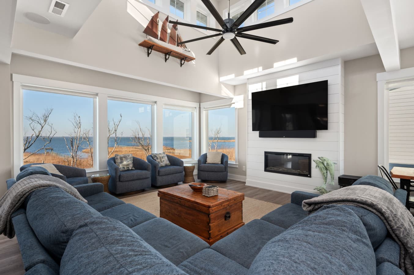 Airy living room w/ plush seating, fireplace, & expansive windows filling the space w/ light