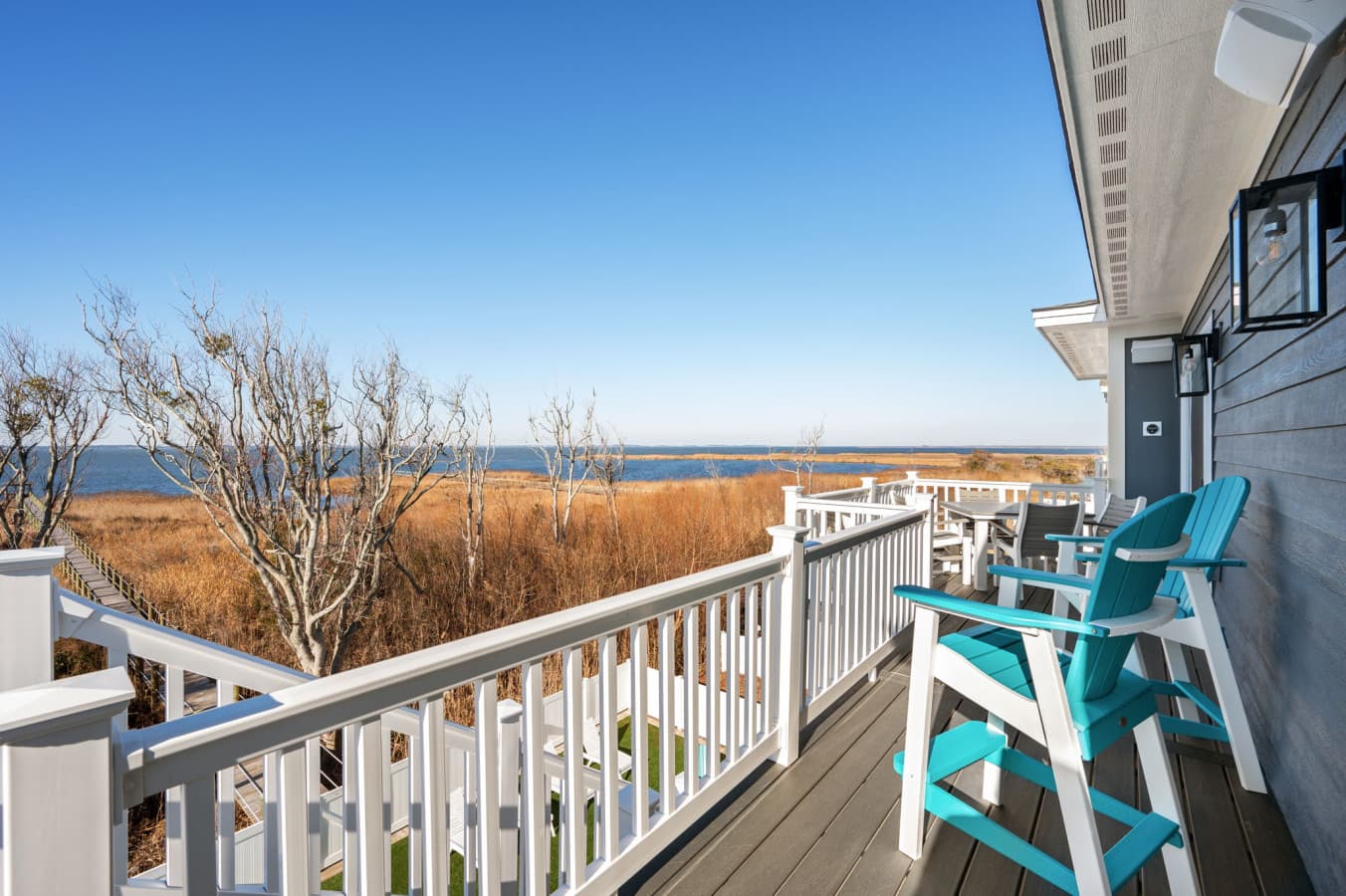Private balcony w/ bright Adirondack chairs overlooking peaceful marshland & open sky