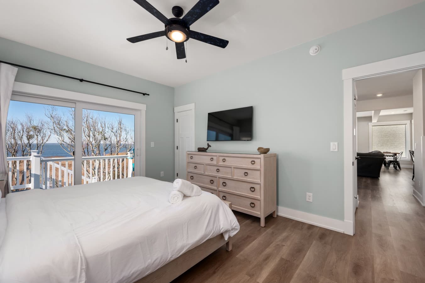 Spacious bedroom w/ dresser, TV, & deck views creating a calm retreat