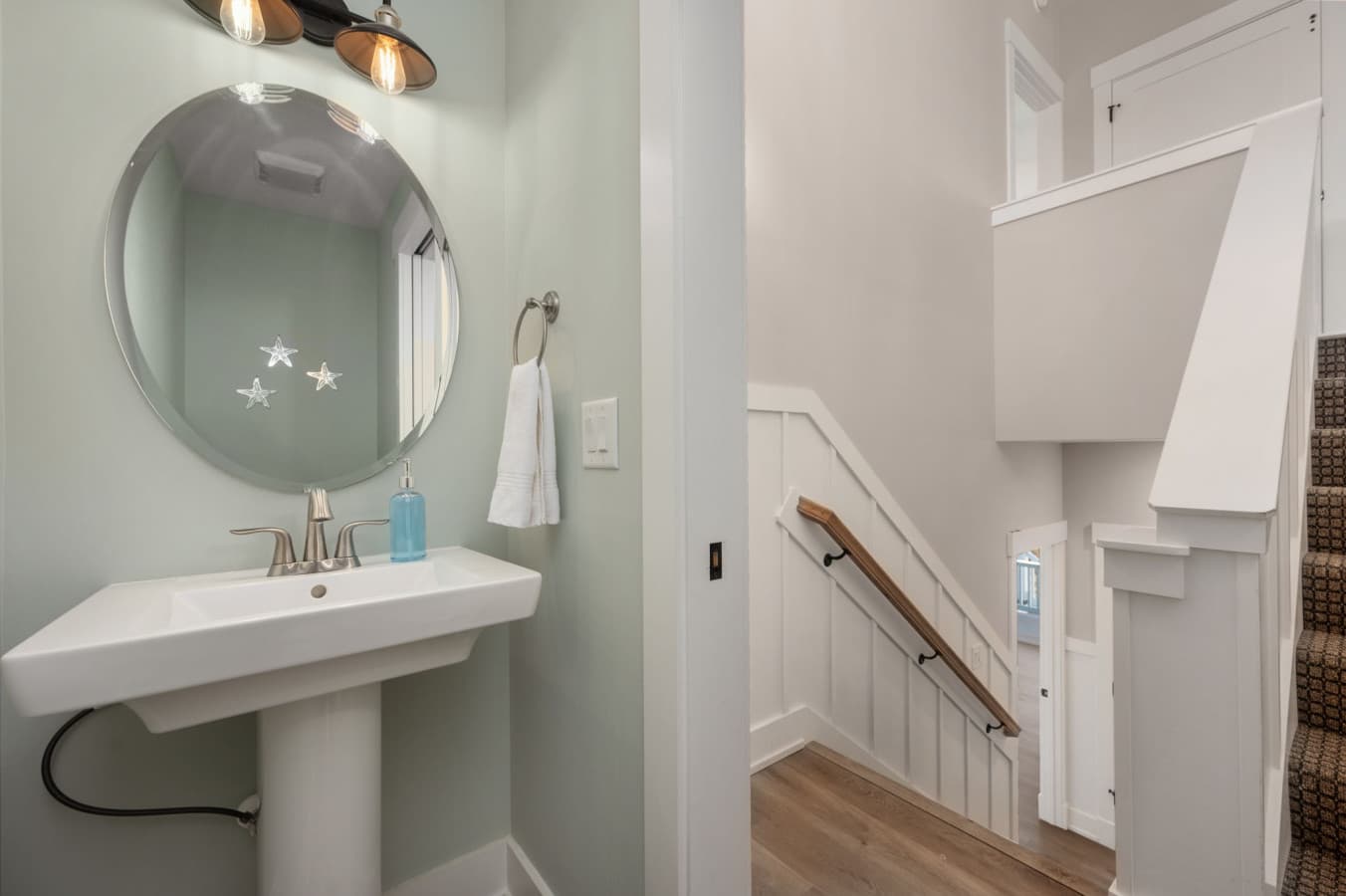 Clean half bath w/ pedestal sink & simple finishes tucked near the stairway