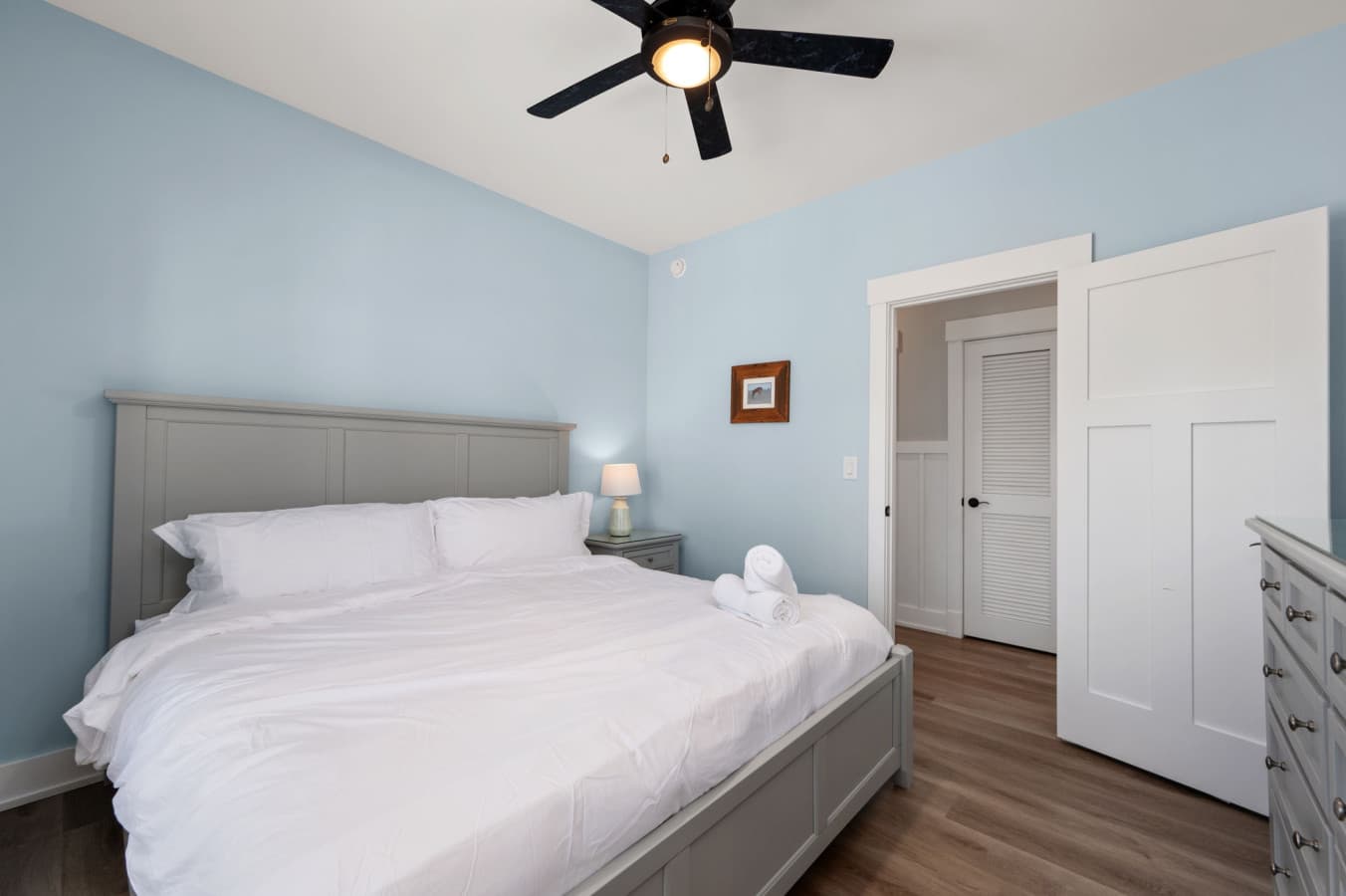 Serene bedroom w/ crisp linens, soft blue walls, & a calm coastal feel