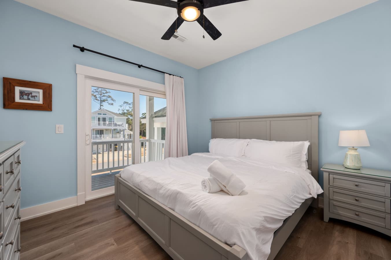 Sunlit bedroom w/ cozy bedding & balcony access through glass doors