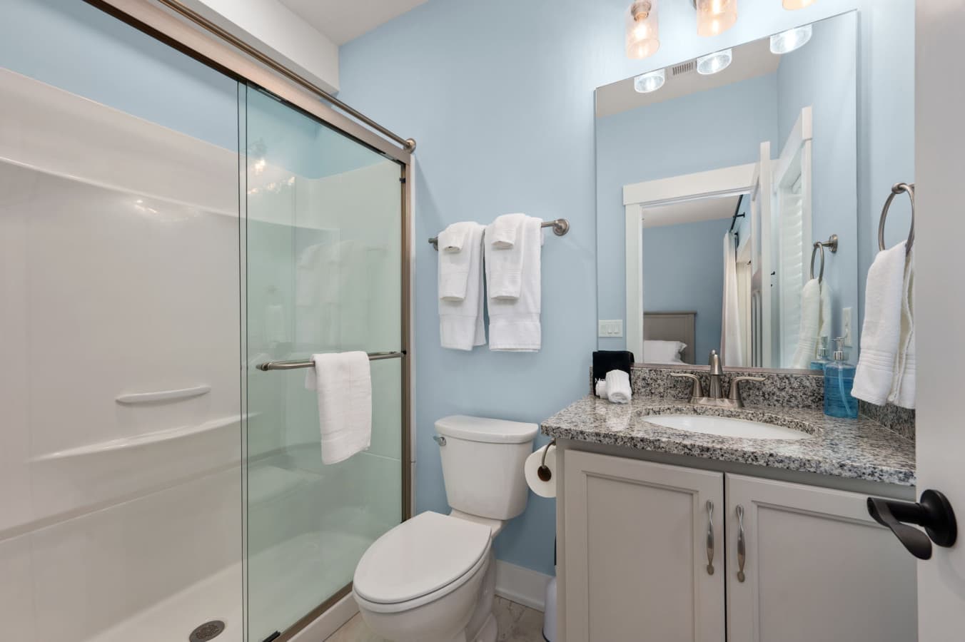 Bright bathroom w/ tiled shower, granite vanity, & fresh white accents