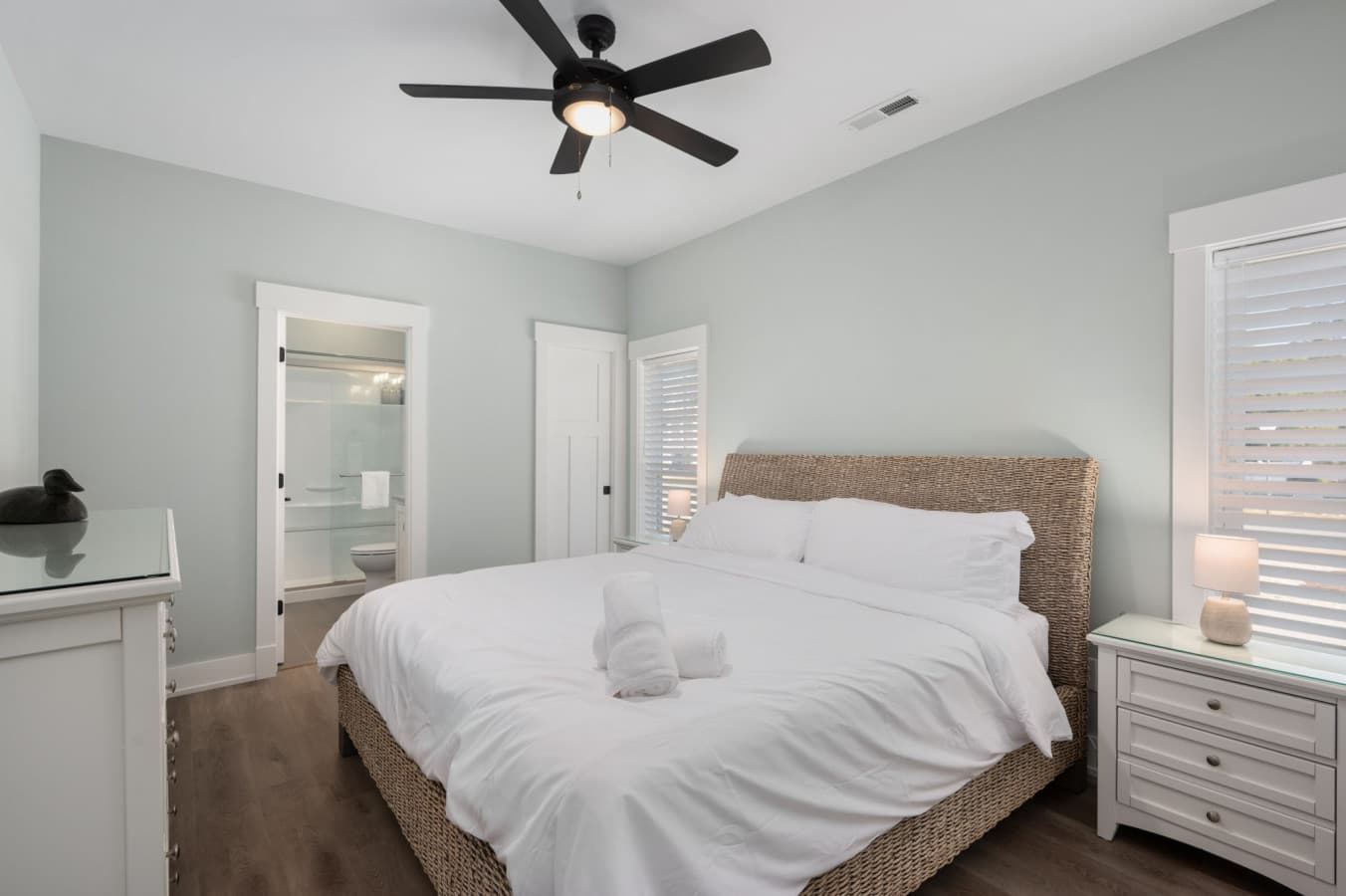 Restful bedroom w/ woven headboard, crisp white bedding & an ensuite bath just steps away