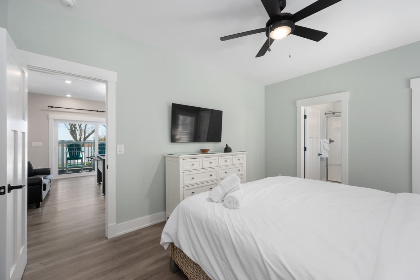 Airy bedroom w/ plush white bedding, wide dresser & wall TV for easy nights in