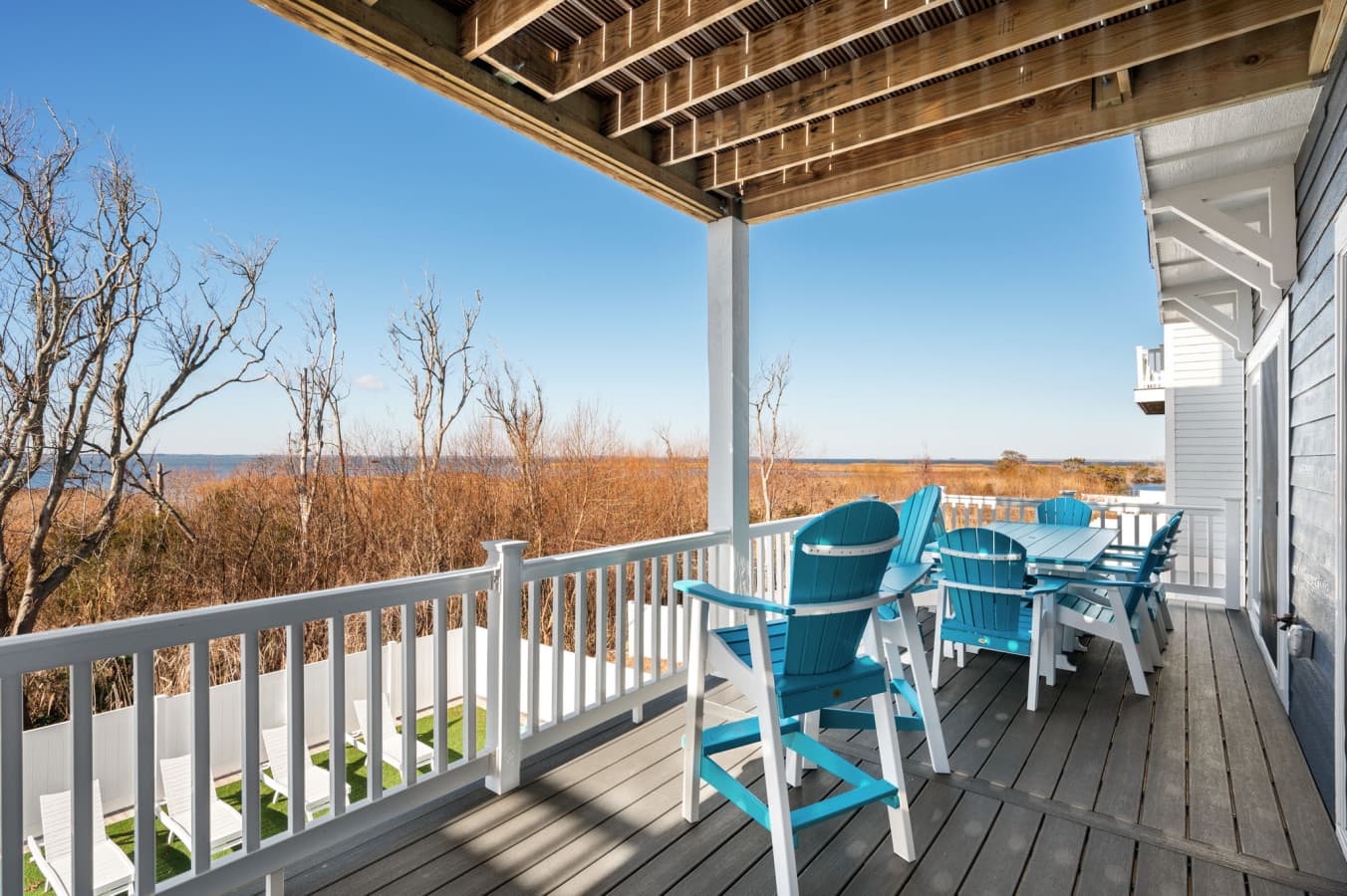 Covered deck w/ turquoise Adirondack chairs & open marsh views for slow afternoons
