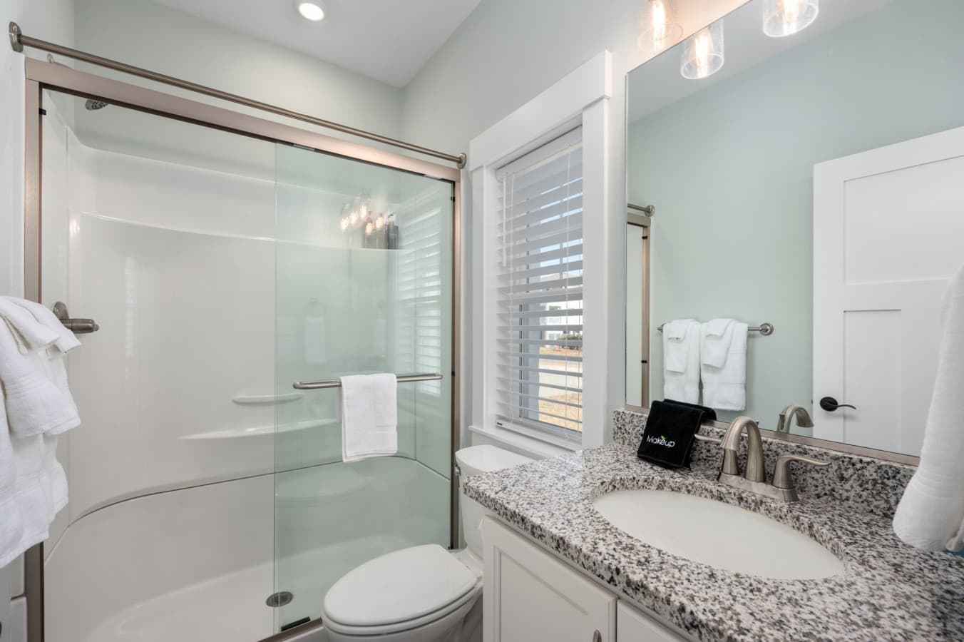 Bright bath w/ glass walk-in shower, granite vanity & plantation shutters for privacy