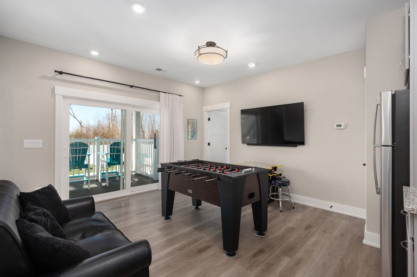Game room w/ foosball, wall TV, leather seating & sliders out to the pool deck
