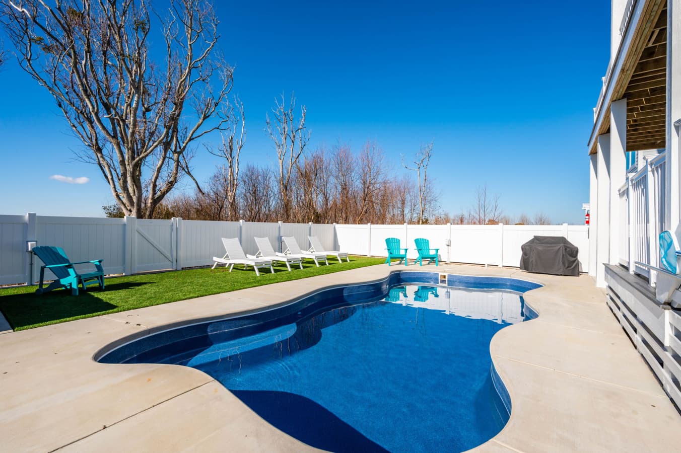 Private pool w/ white loungers, turquoise chairs & a fenced yard for full-day swims