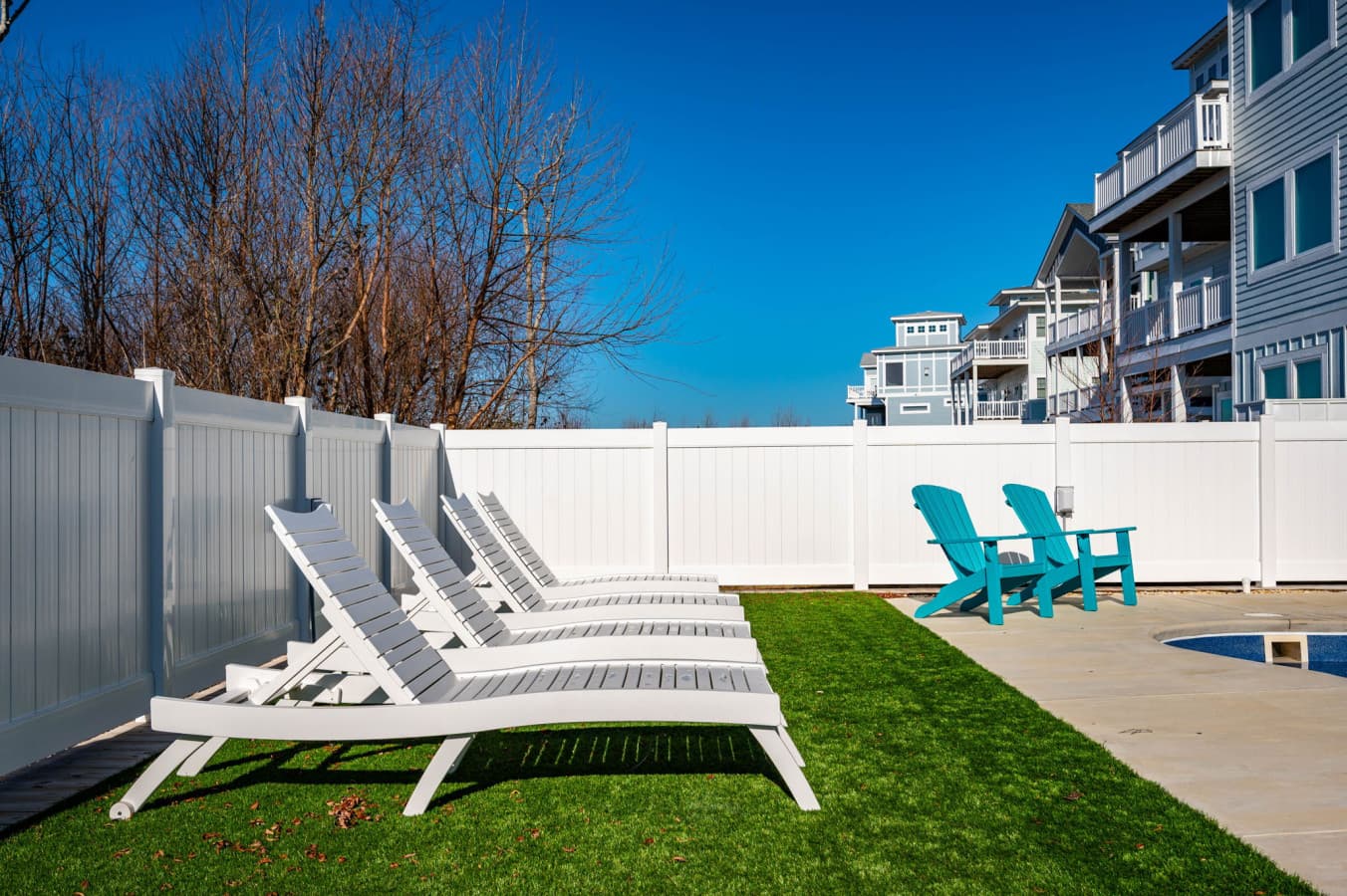 Fenced backyard w/ turf lawn, sun loungers & Adirondack chairs for lazy afternoons