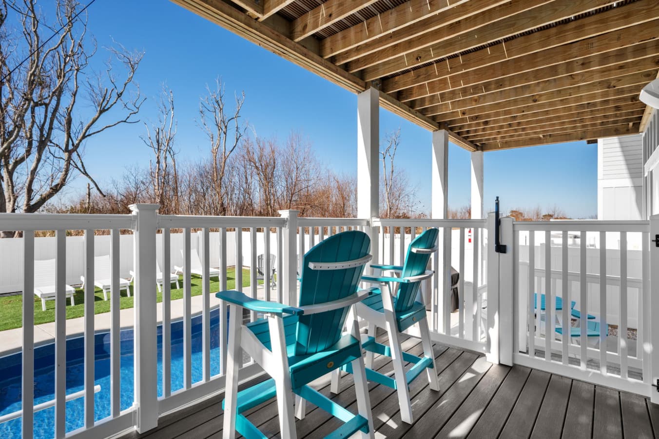 Shaded deck w/ Adirondack chairs overlooking the pool & marsh grass beyond