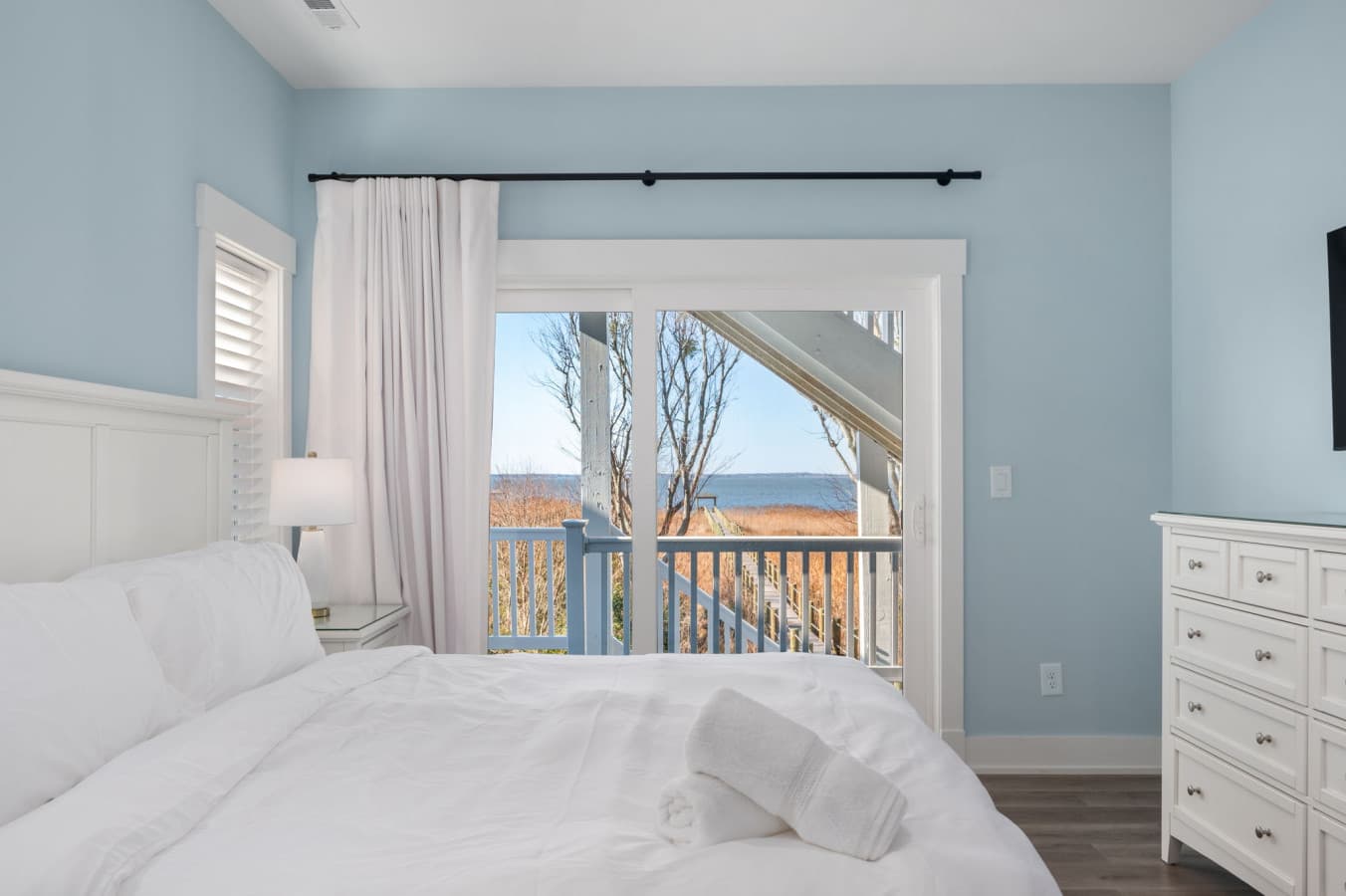 Restful bedroom w/ crisp white bedding, dresser & a deck door for morning air