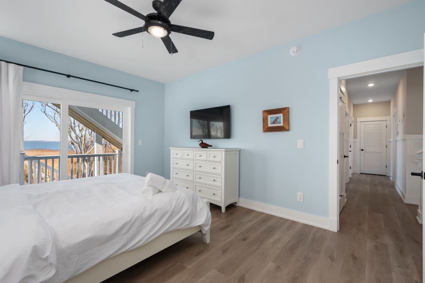 Bedroom w/ deck slider, wide dresser & framed art in soft coastal blues