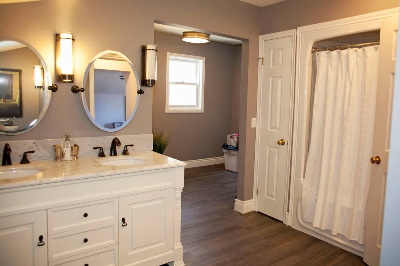 This is the bathroom attached to the master bedroom. Recently renovated with double vanity and mirrors. Just behind here you'll find the front load washer and dryer that is available for your convenience.
