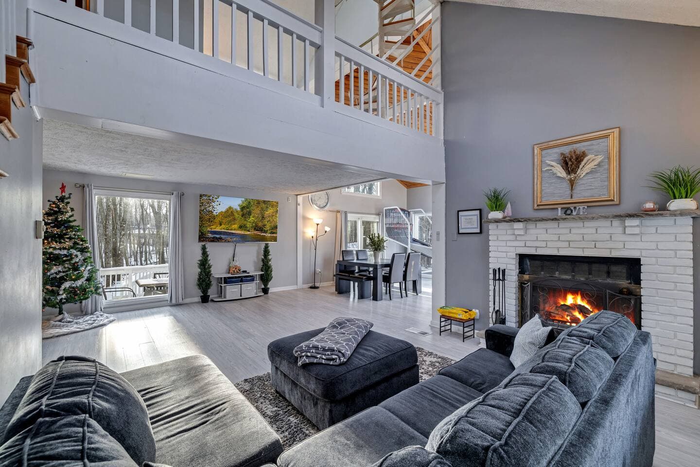 Spacious and inviting living area with a cozy fireplace, vaulted ceilings, and large windows offerin