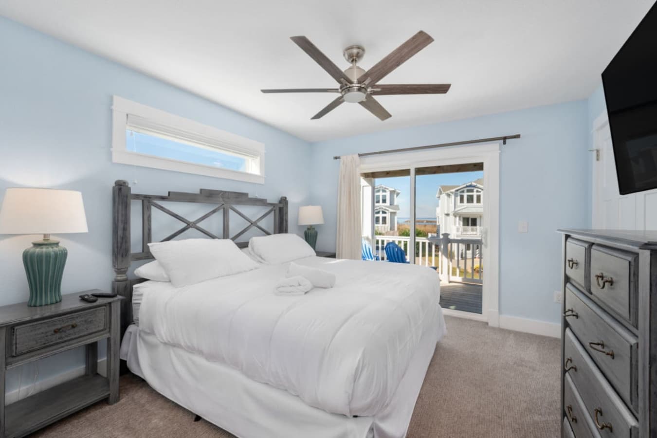 Airy bedroom w/ matching furniture, fan overhead & balcony views beyond