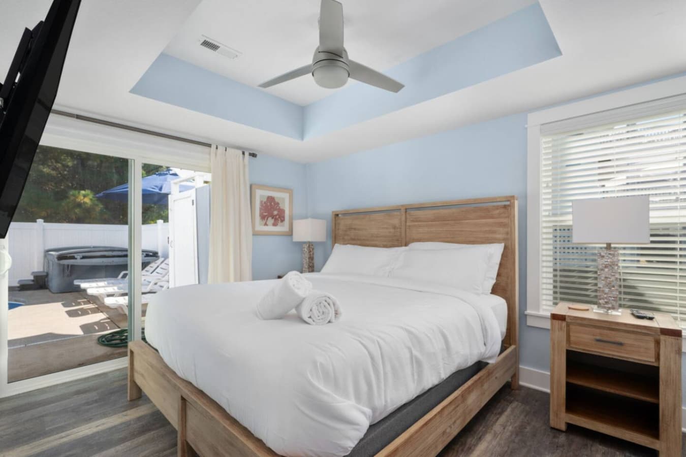 Sunlit bedroom w/ wood headboard, crisp linens & coastal charm