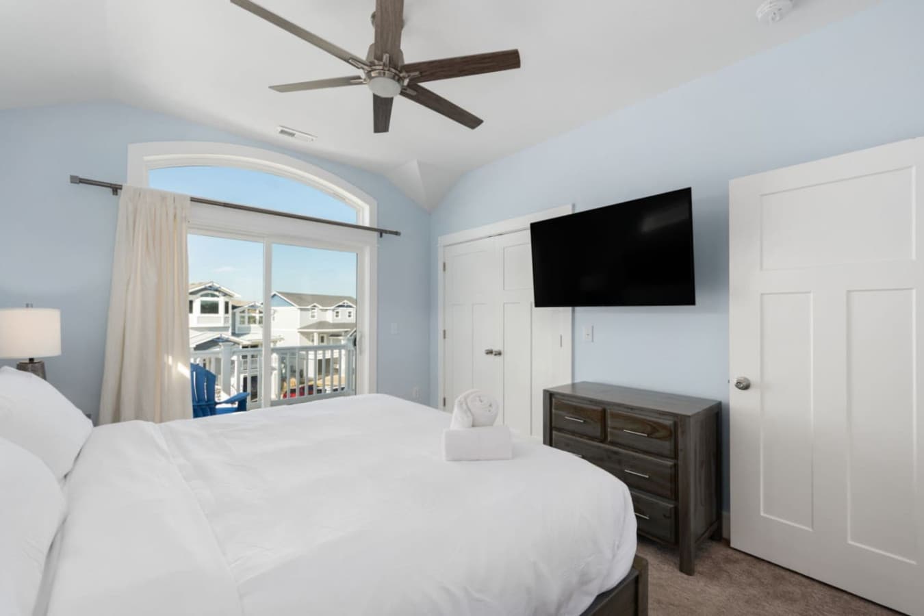 Relaxing bedroom setup w/ TV, ceiling fan & bright outdoor views