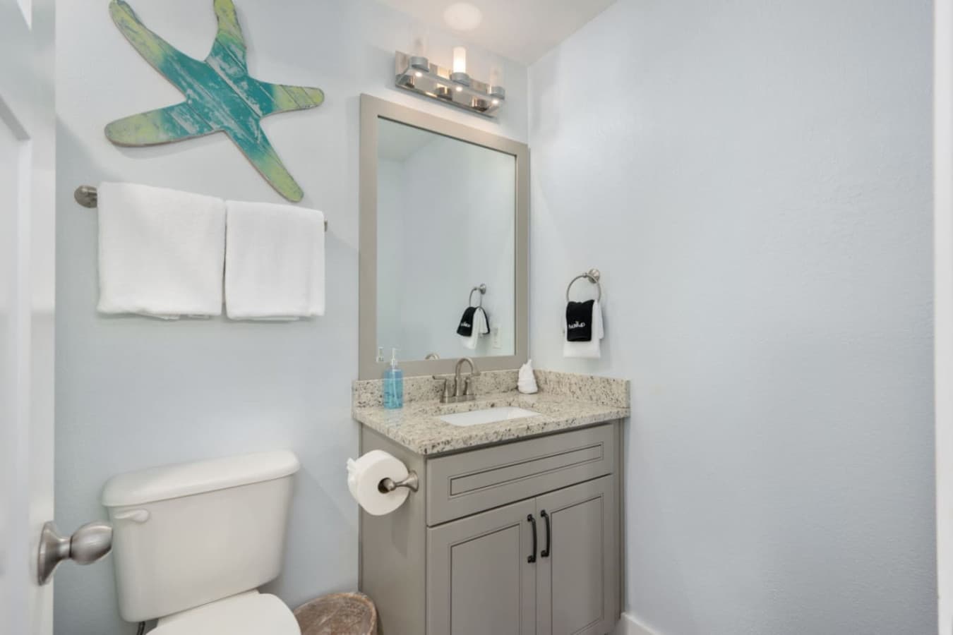 Fresh bathroom w/ granite counter, wall mirror & neatly stocked towels