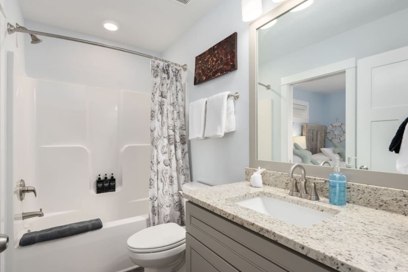 Bright bathroom w/ tub & shower combo, clean finishes & coastal touches