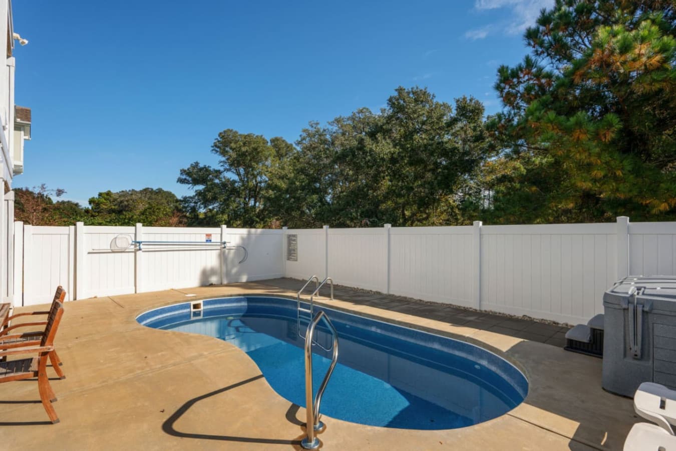 Private pool w/ wooden loungers, sunny concrete deck & full privacy fencing around the yard.