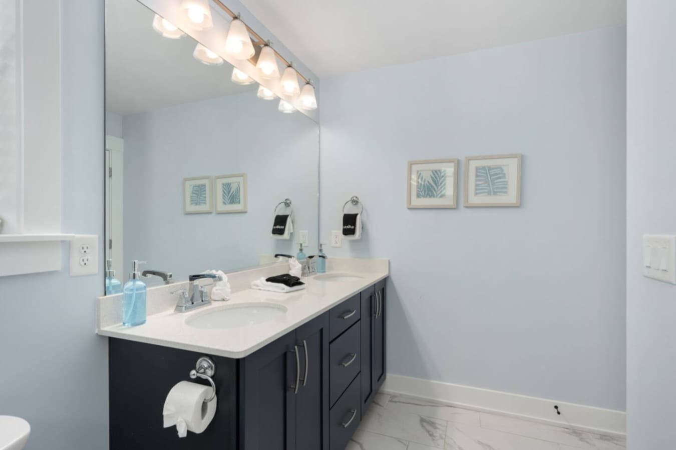 Bright private bath w/ double vanity, clean lines & modern lighting.