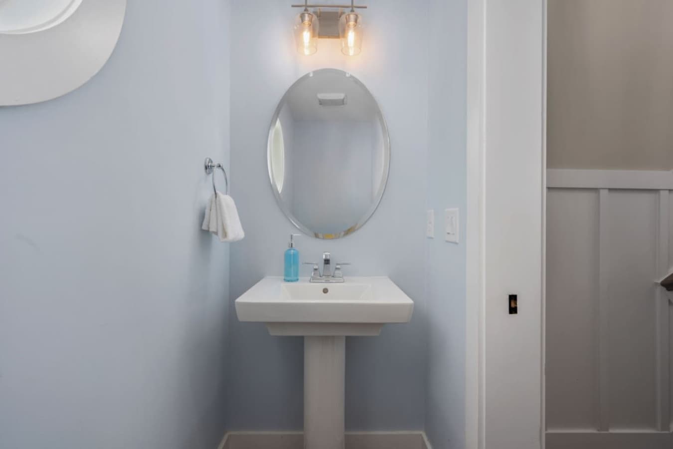 Stylish half bath w/ pedestal sink & simple, coastal-inspired touches.