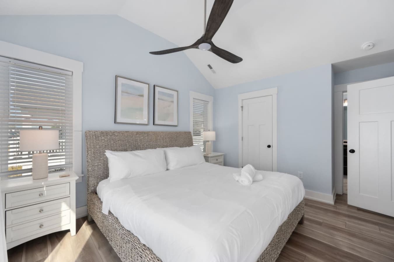 Serene bedroom retreat w/ ceiling fan, natural light & uncluttered design.